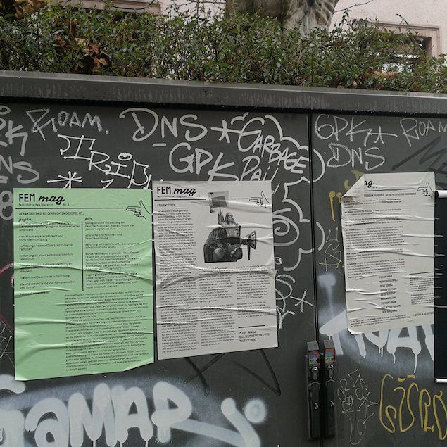 Auf einem Stromverteiler-Kasten mit Graffiti kleben drei Wandzeitungen des Fem.Mag.